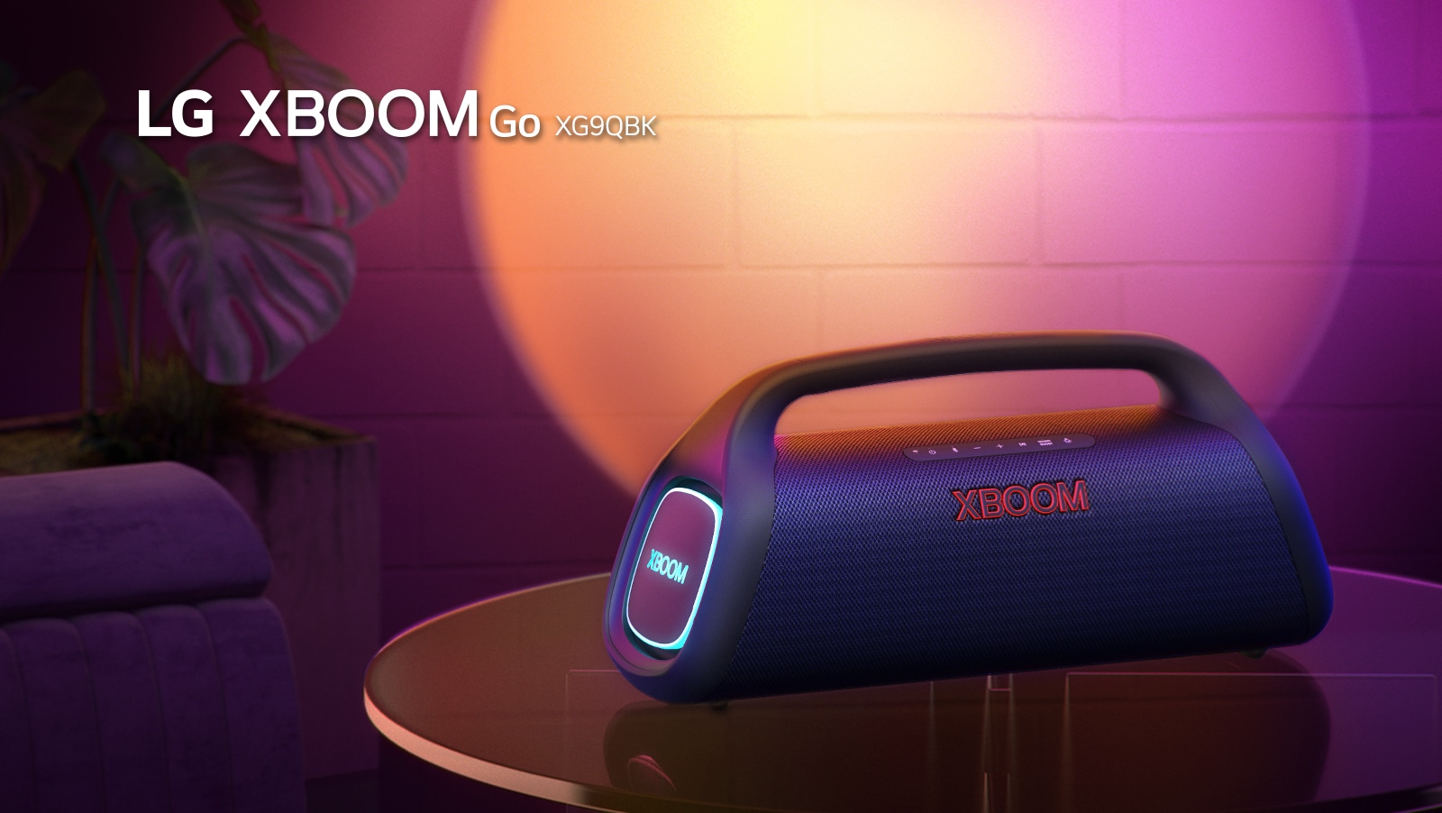 LG XBOOM Go XG9 je položený na kovovom stole so zapnutým oranžovým svetlom. Za stolom je stena osvetlená scénickým svetlom.