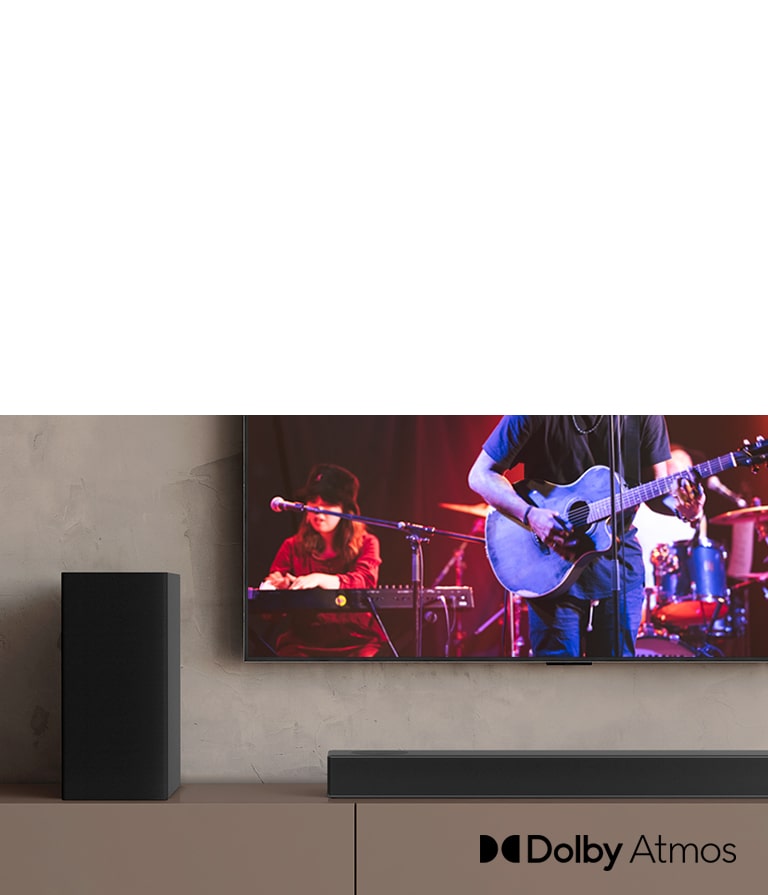 Na LG TV sa zobrazuje koncert a zvukový panel LG je umiestnený pod televízorom. Vľavo na hnedej poličke je zadný reproduktor.