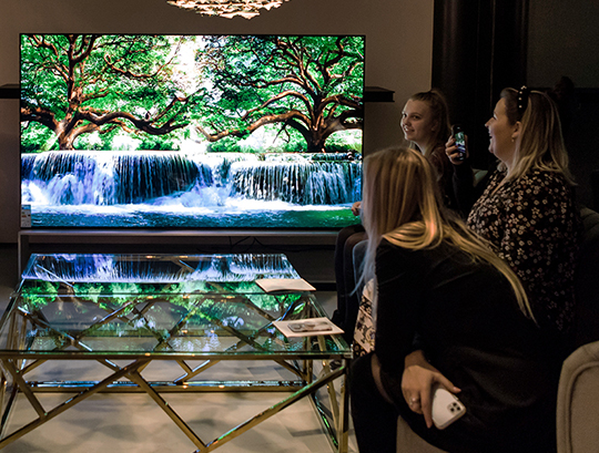 Guests are watching what is being played on LG SIGNATURE 8K OLED TV Z9 while sitting on a couch at the premium event held in London