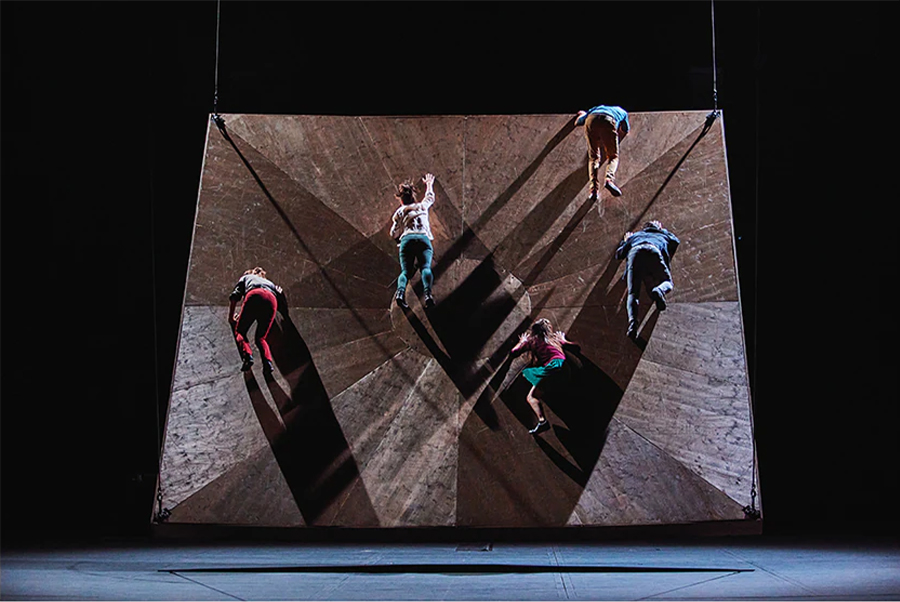 A photo of male and female dancers appearing to fall from an uneven surface.