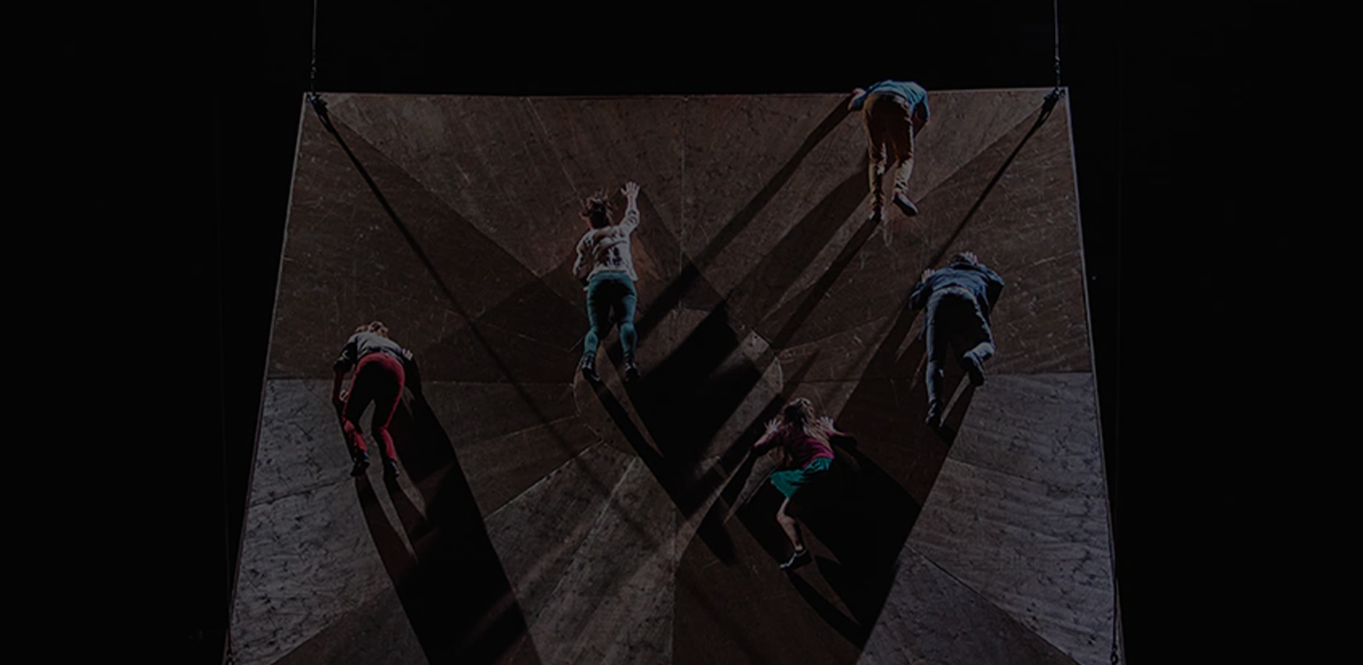 A photo of male and female dancers appearing to fall from an uneven surface.