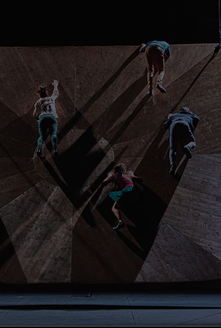 A photo of male and female dancers appearing to fall from an uneven surface.