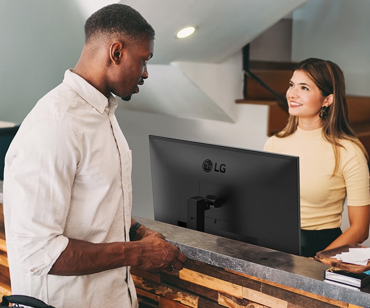 A female receptionist is talking to a man at the front desk.