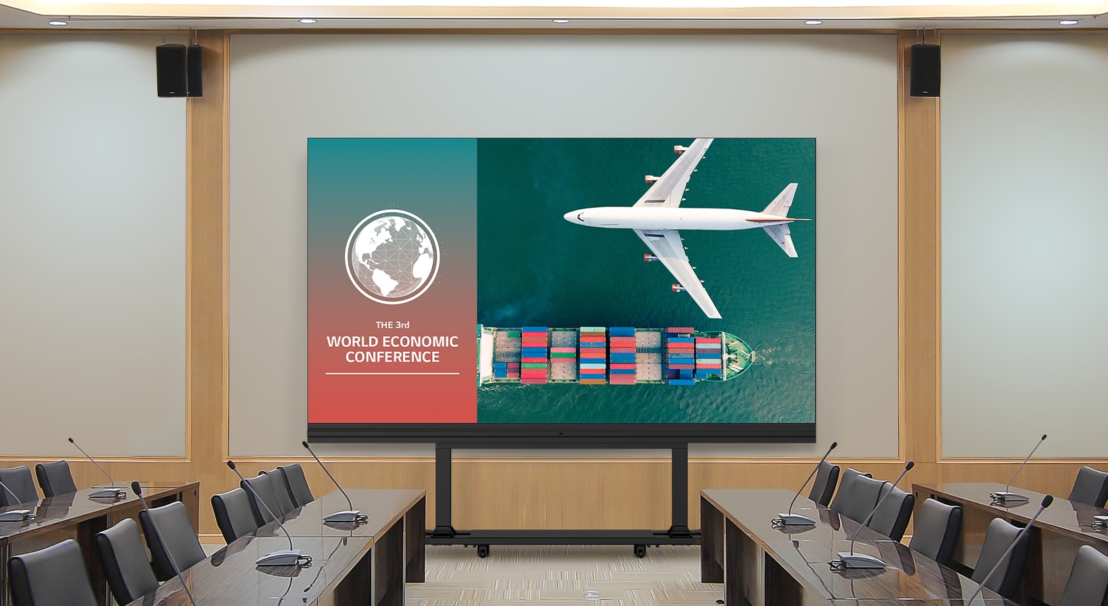 In a spacious meeting room with long tables on both sides, a LABA series which is TAA (Trade Agreements Acts) compliant All-in-One LED model is placed against the wall. The LABA screen displays meeting content vividly.