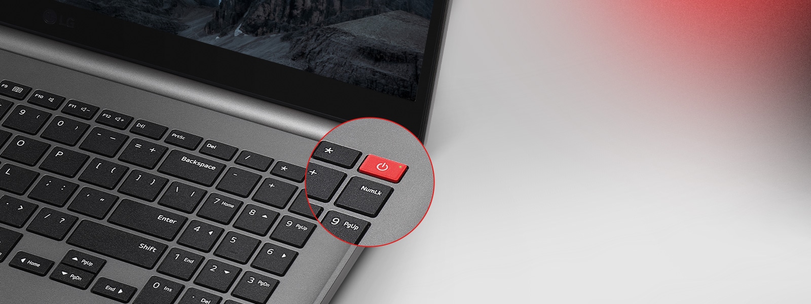 This image shows a close-up of a laptop keyboard. The focus is on a distinctive red power button located in the upper-right corner, highlighted with a circular zoom effect. 