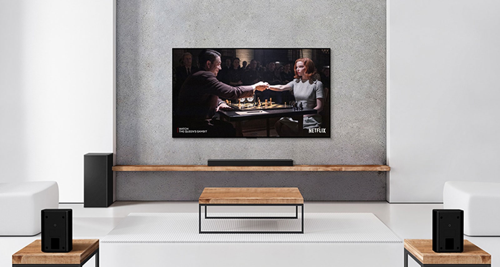 A set of 2 rear speakers, subwoofer, and a soundbar, and TV are in a white living room. A woman and a man are playing chess on TV screen.