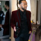 John Legend looks at the camera while holding the bottle of wine.