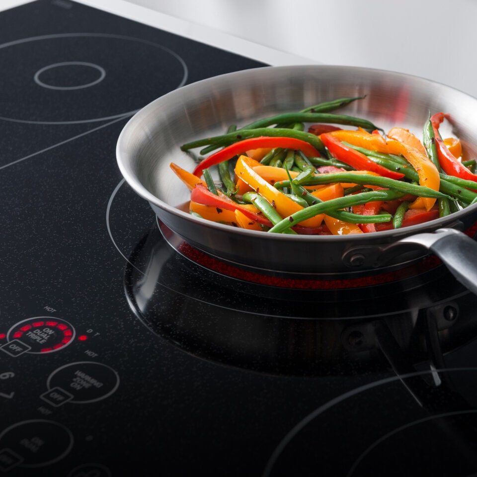 A pan filled with colorful vegetables cooking on an electric stove with visible controls. The word 'Electric' is displayed in the bottom corner.