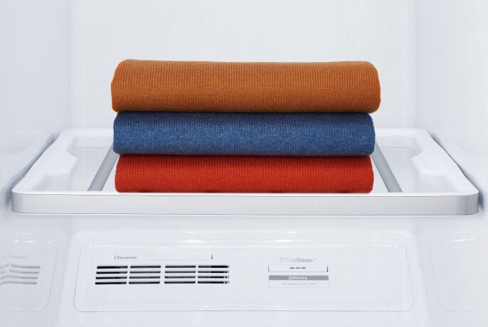 Stack of colorful folded clothes on the drying rack inside an LG Styler.