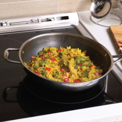 Person cooking stir fry on an electric stovetop, showing the even heat distribution and smooth glass surface.