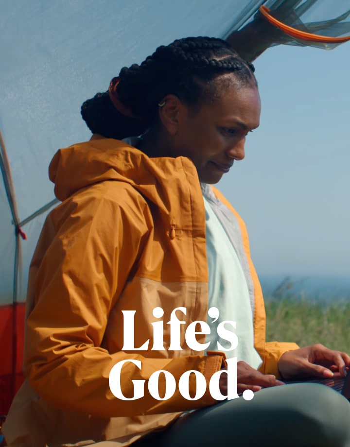 A woman in a yellow jacket using an LG gram outdoors, looking relaxed and focused.