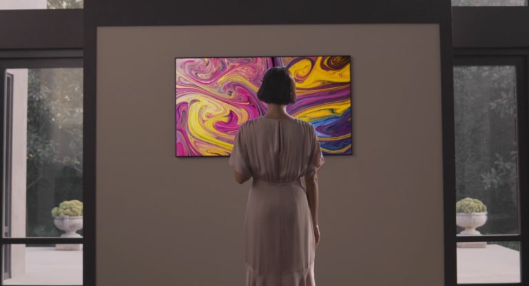 A woman who has a gallery TV wall-mounted in a gallery-like house sees a gallery TV stand and looks at them emotionally