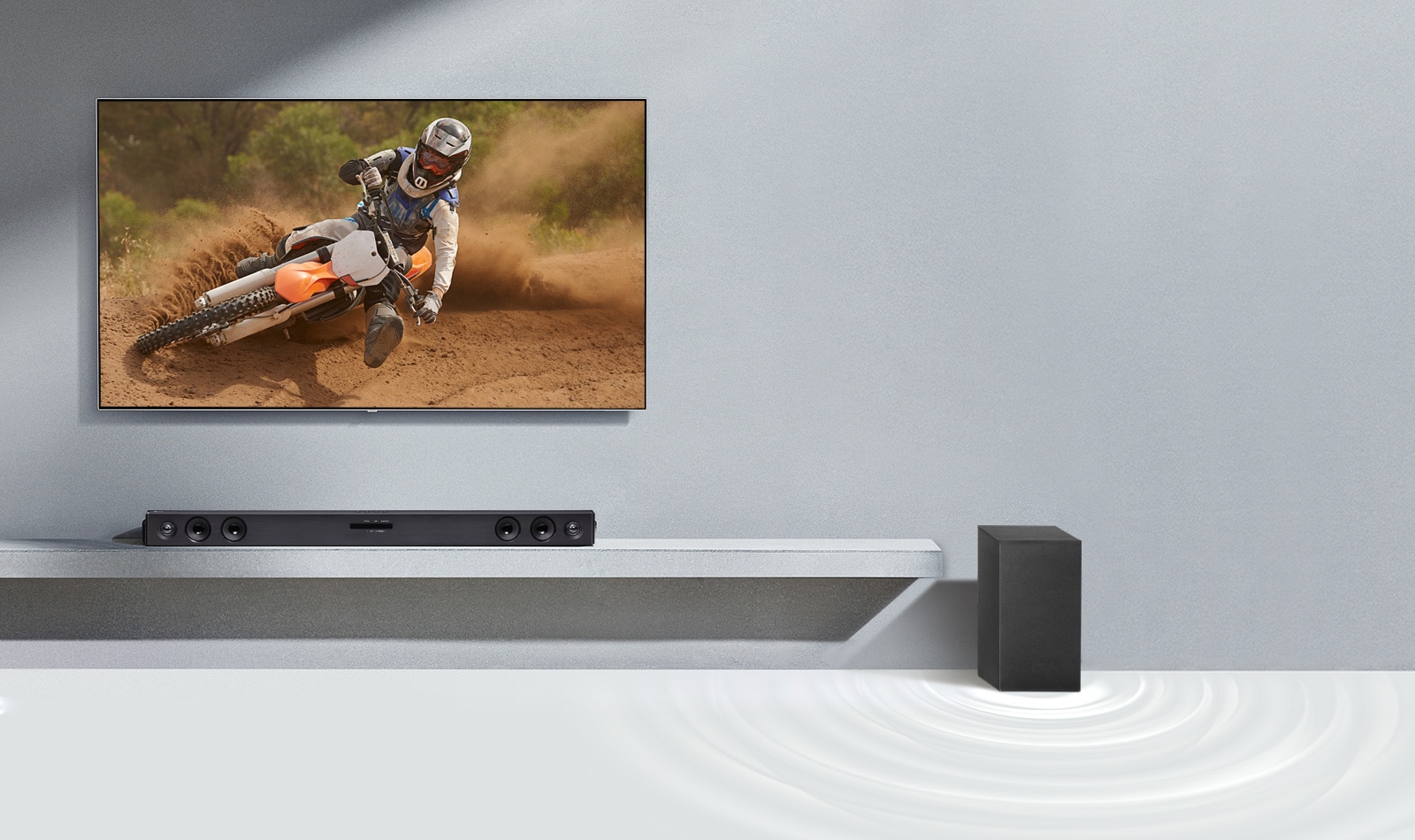 LG sound bar SQC2 and LG TV are placed together in the living room. The subwoofer is placed next to the sound bar. The TV is on, displaying a mortorcycle image.