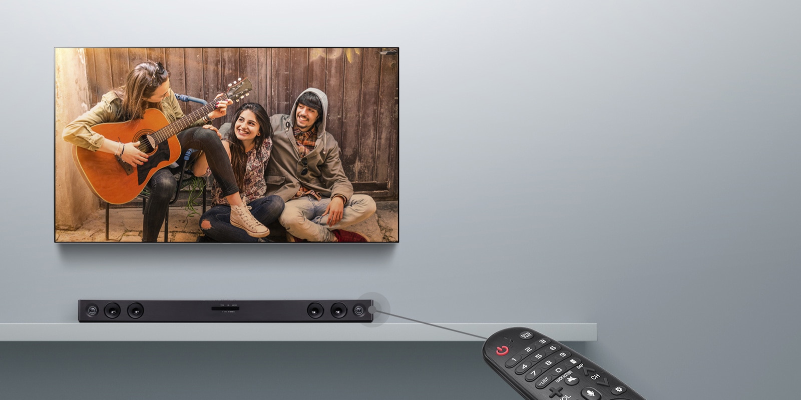 LG TV is hung on the grey wall, displaying a movie scene. And the sound bar is placed below. A remote is shown on the right side of the image. There is a line connected to the sound bar to illustrate that users can control the sound bar with their remote.